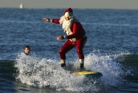 Seal Beach, UNITED STATES:  Michael Pless, dressed in a Santa wetsuit and beard enjoys a Christmas eve surf at Seal Beach, California, early 24 December 2006.  Warm temperatures are forcast for Christmas in southern California.  Pless, a surfing instructor, also has a tuxedo wetsuit for New Years eve.  AFP PHOTO / Robyn BECK  (Photo credit should read ROBYN BECK/AFP/Getty Images)