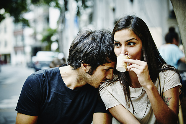 Couple sitting on bench outside city cafe drinking espresso man resting head on woman's shoulder