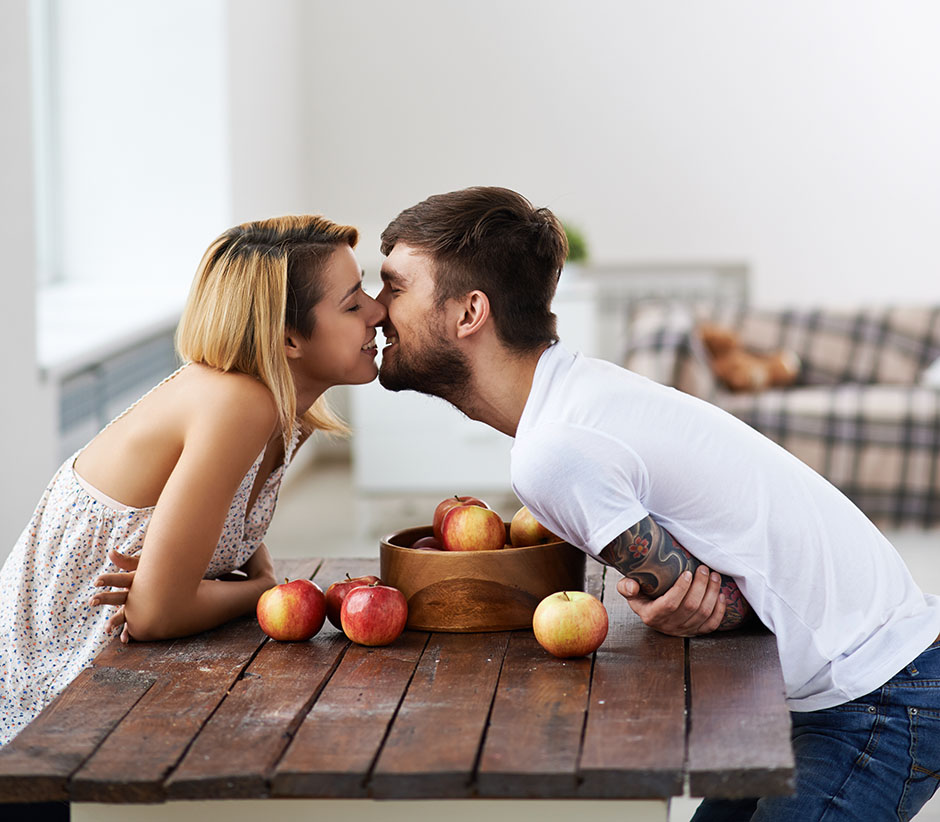 man and woman kissing sitting at table