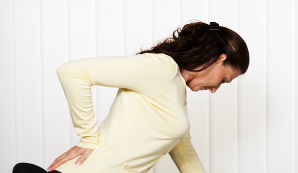 Woman with back pain of the intervertebral disc with office work at the desk.